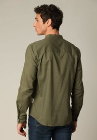 Olijfgroen shirt met lange mouwen en een button-down kraag, met een gladde textuur en een label aan de onderste zoom.