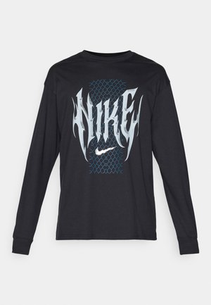 Juodas ilgomis rankovėmis T-shirt su mėlynu tinkleliu ir didžiu baltu "NIKE" tekstu, turinčiu ugnies akcentus.