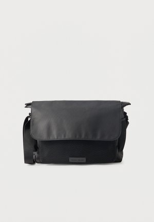 Sac messager noir avec fermeture à rabat et poche avant texturée, bandoulière réglable, et design minimaliste sur fond uni.