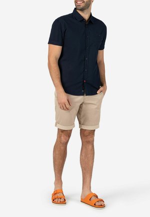 Herren Kurzarm-Hemd in Marineblau, hellbeige Rollshorts und orangefarbene Schlupfsandalen. Lässige Passform und atmungsaktives Material.