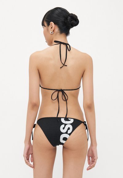 Black bikini with a textured fabric. Top features thin straps that tie at the neck and back. Bottoms have side ties and a large white logo design.