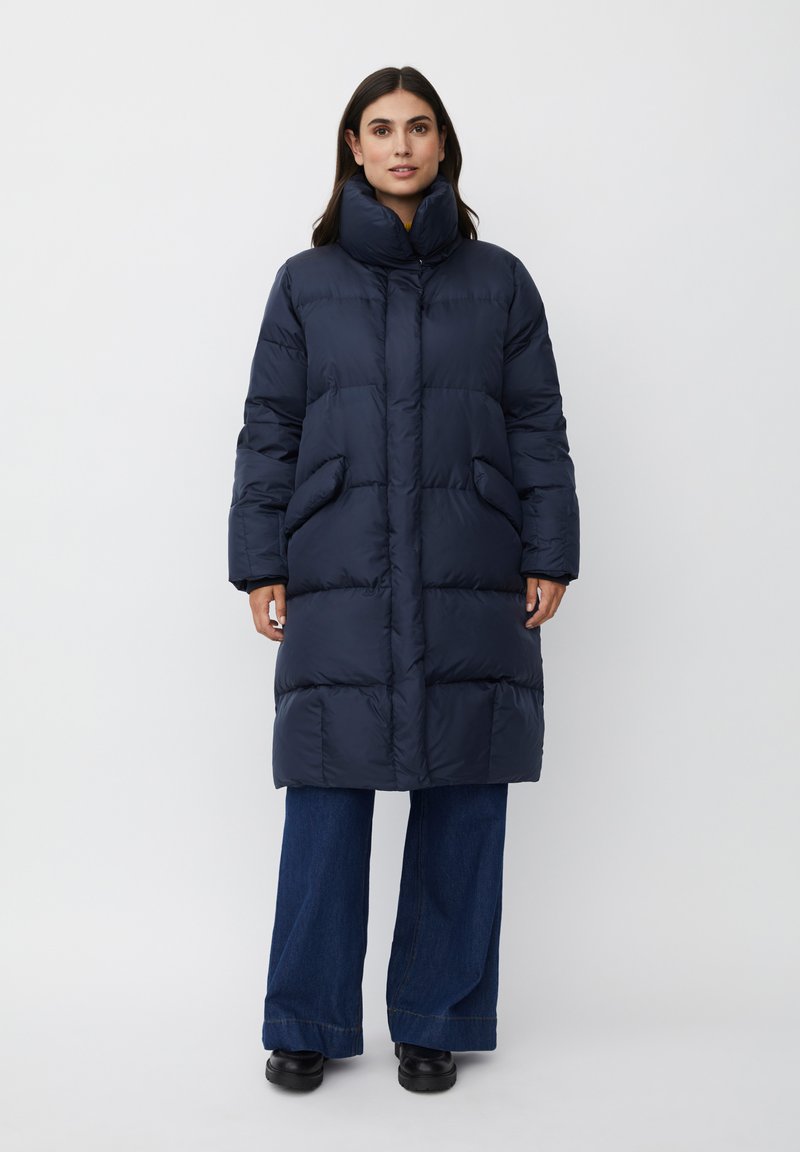 Cappotto imbottito blu navy con colletto alto, due tasche frontali e design trapuntato. Il materiale appare liscio con una texture leggera.