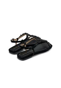 Sandali neri con tomaia in suede texturizzato, decorati con perline nere, suola piatta e cinturino alla caviglia regolabile.