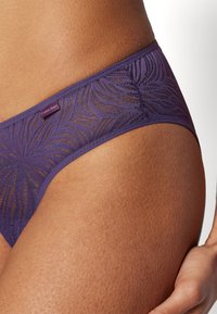 Lila csipkeborítású tanga hullám mintázattal, sima elasztikus derékpánttal és egy kis Calvin Klein logó címkével. Puha tapintású.