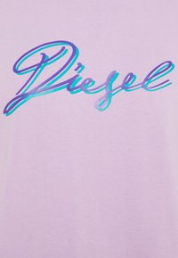 Purple and turquoise script text "Diesel" on a light purple fabric background, showing close-up of printed clothing detail.