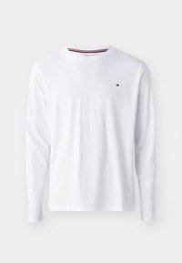 Hvid langærmet t-shirt lavet af bomuld. Har en rund hals med en rød og blå stribe inden i kraven og et lille logo på venstre bryst.