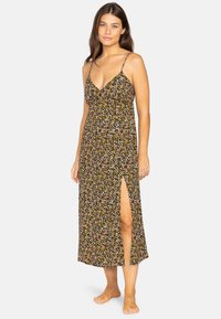 Abito maxi nero con stampa floreale, caratterizzato da spalline sottili e regolabili e uno spacco laterale alto fino alla coscia. Realizzato in tessuto leggero.