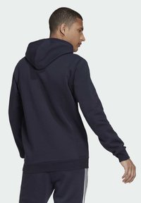 adidas Sportswear ESSENTIALS FLEECE - Jersey con capucha - blue