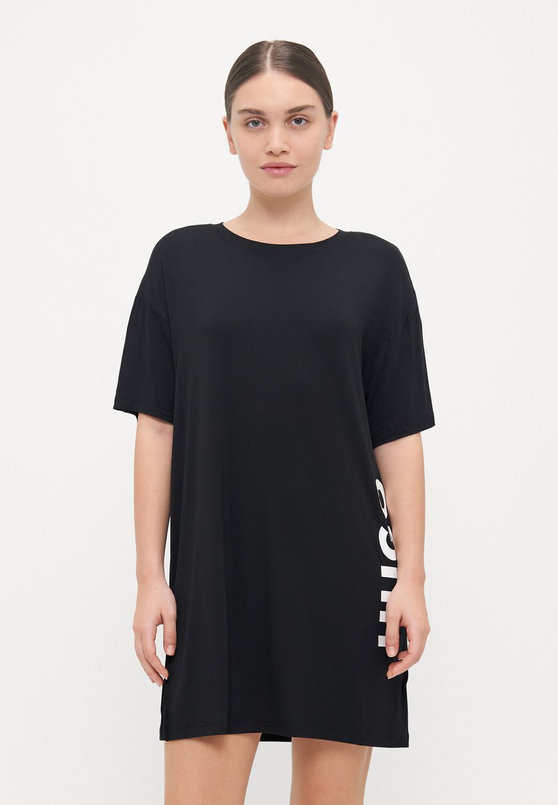Juoda per didelė t-shirt su trumpomis rankovėmis, apvaliu kaklu ir balta grafika šone. Minkšta, lygi medžiaga, laisvas fasonas.