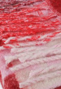 Rød og lyserød gradient uldsyg med frynset kanter, der har en blød tekstur og lagdelte, varierede mønstre gennem hele.