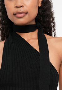 Μαύρο ριμπ λαιμόκοψη τοπ με ευρεία λαιμόκοψη και κόμπο γύρω από το λαιμό, κατασκευασμένο από καπιτονέ ύφασμα.