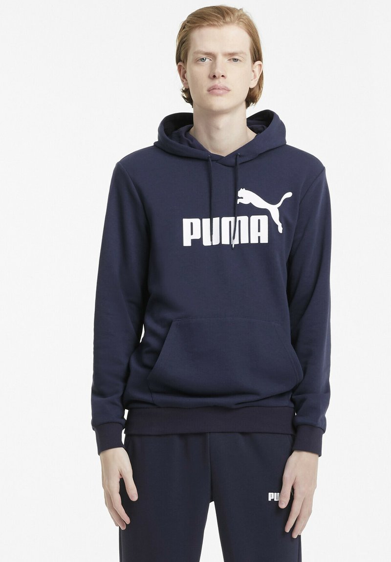 Námořnická modrá mikina z měkkého materiálu, s velkým bílým logem "PUMA" a klokaní kapsou vpředu. Klasický střih s šňůrkami.