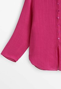 Fuchsia blouse with long sleeves, lightweight fabric, button closure, and a slightly curved hem. Features 10 matching buttons along the placket.