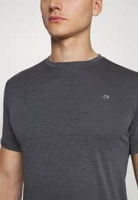 Dark gray crew-neck t-shirt made of soft material, featuring short sleeves and a small embroidered CK logo on the chest.