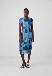 Modrá tie-dye midi šaty s okrúhlym v�ýstrihom, krátkymi rukávmi, jemnou textúrou a priliehavým strihom, doplnené striebornými sandálmi na blokovom podpätku.