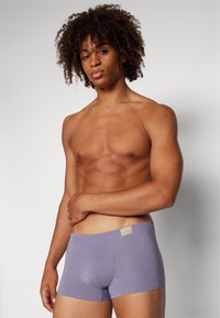 Lila Baumwoll-Boxershorts mit weichem Material, die ein minimalistisches Design und dezente Markenkennzeichnung am Bund aufweisen.