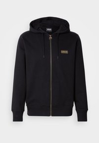 Black zip-up hoodie made of soft fabric, featuring a gold logo patch, drawstring hood, and ribbed cuffs and hem.