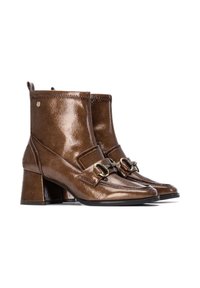 Botas de tobillo de cuero marrón con un acabado brillante, punteras cuadradas, tacones planos y acentos de hardware en tono dorado en las correas frontales.