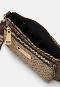 Borsa a tracolla marrone con motivo, esterno testurizzato, zip dorate, fodera nera e placca con logo frontale. Inclusa la tracolla regolabile.