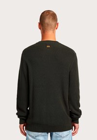 Maglione verde scuro a maglia con texture a costine, maniche lunghe e scollo rotondo. Presenta una piccola etichetta del marchio sul retro.