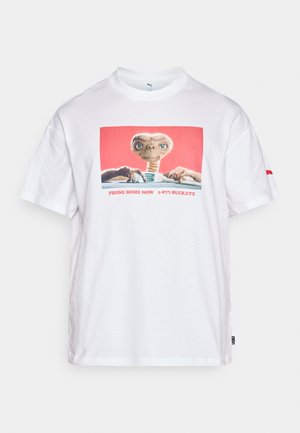 Valge puuvillane T-särk, millel on graafiline trükk tulnukast, kellel on vintage telefon, ja allpool tekst "PHONE HOME NOW 1-877-BUCKETZ".