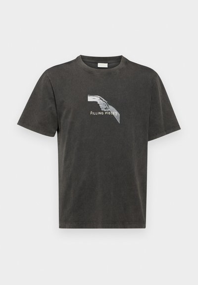T-shirt en coton gris foncé avec une coupe décontractée, présentant un design graphique d'une main et le texte "Filling Pieces" en blanc.