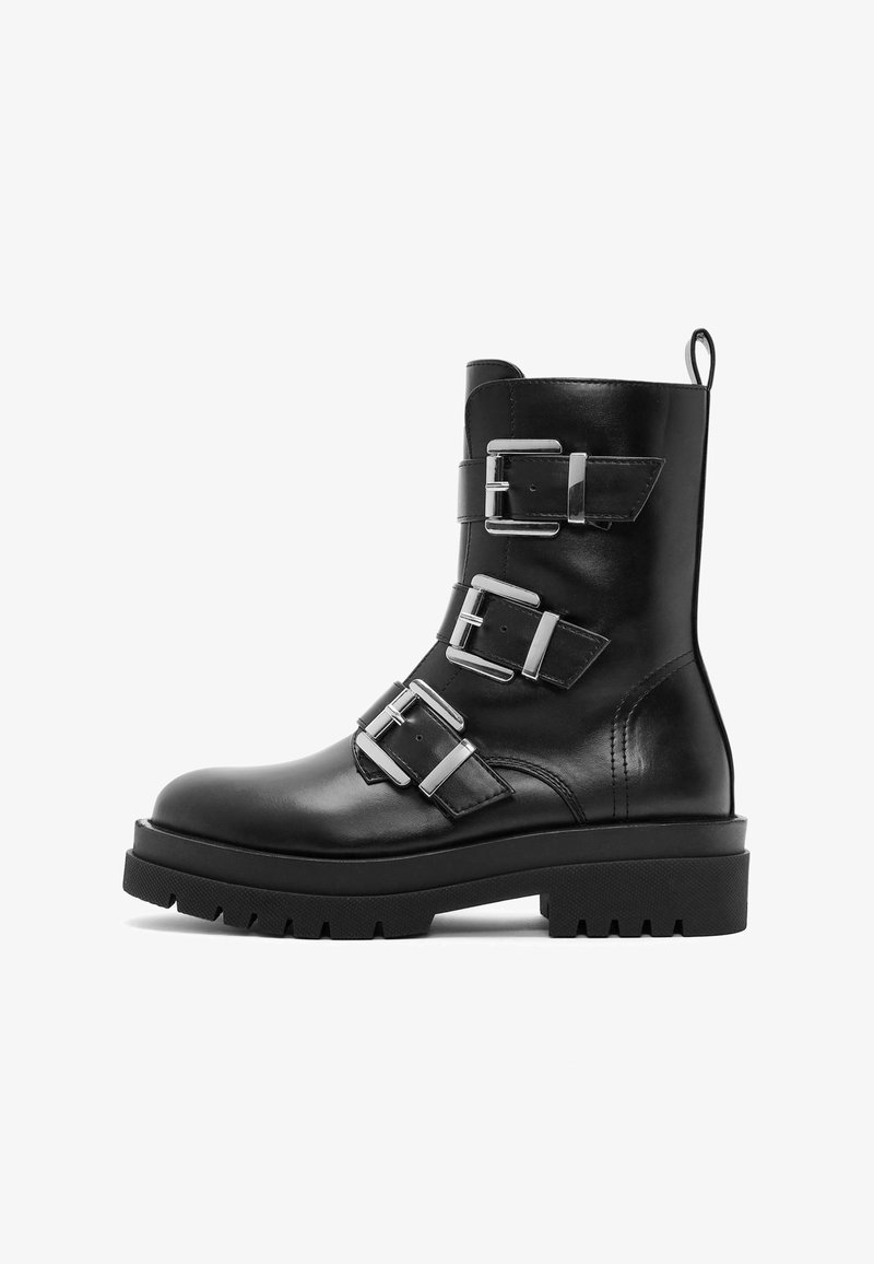 Black leather ankle boot with three silver buckles, a textured tread sole, and a pull tab, featuring a sleek design and sturdy construction.
