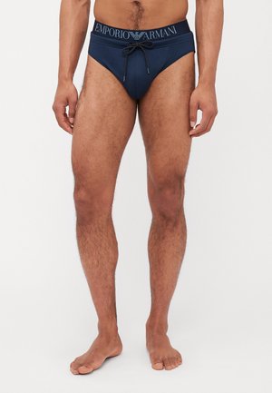 Marineblå svømmeshortser fra Emporio Armani, med snøring i livet og logo på linningen, lavet af glat, strækbart materiale.