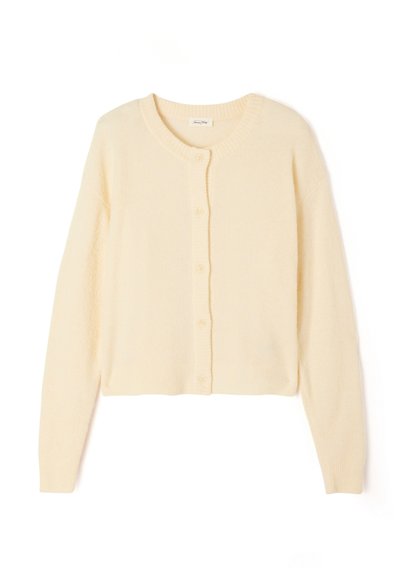 Cardigan court beige clair en tricot doux, avec un col rond, une fermeture à boutons, et des poignets et un ourlet côtelés.