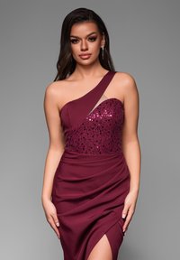 Robe bordeaux à une épaule, avec un corsage en sequins et une jupe drapée avec une fente haute, fabriquée en tissu lisse et texturé.