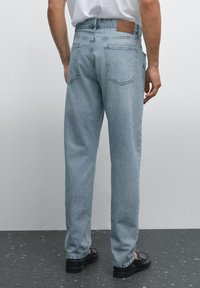 Ljusblå denimjeans med hög midja, rak bendesign, två bakfickor och en brun läderlapp på midjebandet.
