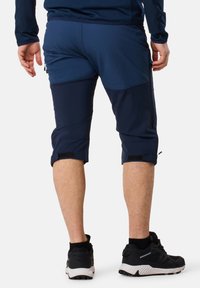 Marinstinna knälängd sportshorts med en slät yta, sidofickor med dragkedja och kardborreband vid fållen.