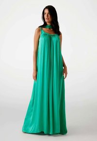 Langes, fließendes grünes Kleid aus leichtem Stoff mit breiten Trägern, einem elastischen Ausschnitt und einer lockeren A-Linien-Silhouette.