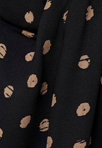 Schwarzer Stoff mit unregelmäßigen, beigen Punkten, weiche Textur und leichtes Design, geeignet für verschiedene Bekleidungsanwendungen.