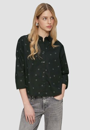 Zwarte button-up shirt met witte hartpatronen, lange mouwen en een relaxed fit. Gepaard met grijze jeans, heeft een gladde textuur.