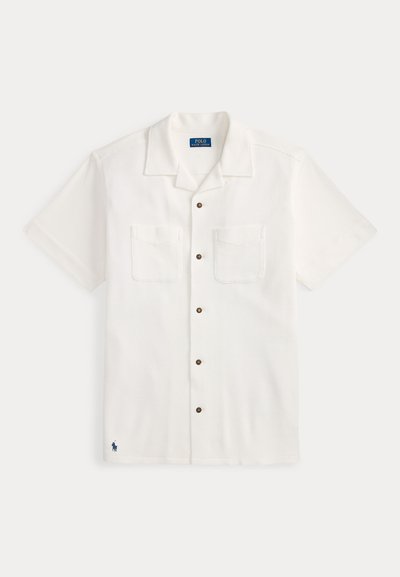 Άσπρο πουκάμισο με κοντό μανίκι και κουμπιά, με υφή σε μοτίβο, δύο τσέπες στο στήθος και καφέ κουμπιά. Κεντημένο λογότυπο στη βάση.