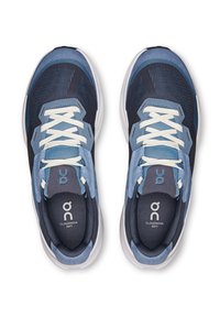 Scarpe sportive blu e navy con tomaia in mesh, dettagli in suede e lacci bianchi. Presentano un logo e un design della suola ammortizzata.