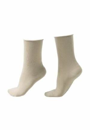Deux chaussettes beige jusqu'à la cheville présentées debout sur un fond blanc.
