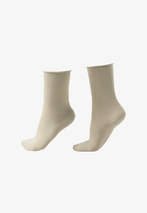 Zwei beige knöchellange Socken, aufrecht vor weißem Hintergrund dargestellt.