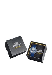 Reloj Festina con caja redonda de acero inoxidable y correa de goma azul. El dial blanco y azul cuenta con múltiples sub-diales, presentado en una caja negra.