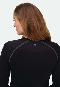 Zwarte top met lange mouwen, ronde halslijn en contrasterende grijze stiksels langs de schouders. Klein logo op de bovenrug.