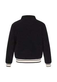 Sort kordfløjljakke med krave, lange ærmer og hvidstribede ribbede manchetter og kant. Bagtil er der en vertikal tekstur.