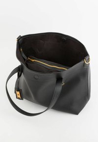 Sort tekstureret læder tote taske med en bred åbning, guld hardware-detaljer, indvendig lynlåslomme og en lang skulderrem.