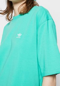 Turquoise cotton oversized t-shirt featuring a crew neck and short sleeves, with a small white logo on the chest.