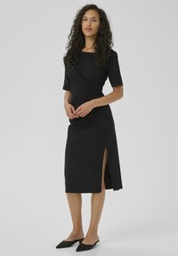 Black, ankle-length dress with a square neckline, short sleeves, side slit, and wrap design; made of smooth, lightweight fabric.