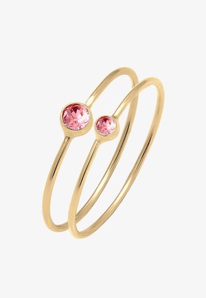 To tynde gyldne ringe, hver sat med en rund lyserød ædelsten, en større og en mindre, vist mod en hvid baggrund.