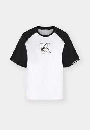 Λευκό και μαύρο raglan t-shirt με μεγάλο περιγραμματικό γράμμα K και μικρό σκυλί με γυαλιά ηλίου τυπωμένα στο στήθος.