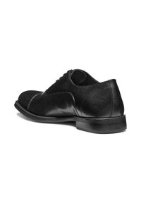 Chaussure habillée en cuir noir avec une finition lisse, bout rond et design à lacets. Talon légèrement surélevé et détails de couture courbés sur les côtés.