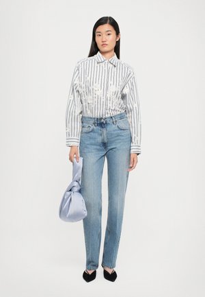 Triibuline valge ja hall nööbiga särk lillekirjaga, koos siniste sirgete teksade ja helesinise sõlmitud kotiga. Mustad terava ninaga kingad.