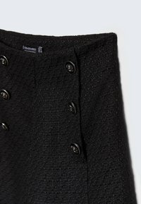 Černý texturovaný blazer se strukturovaným designem, pěti kovovými knoflíky na přední straně a hladkým vnitřním podšitím pro pohodlí.